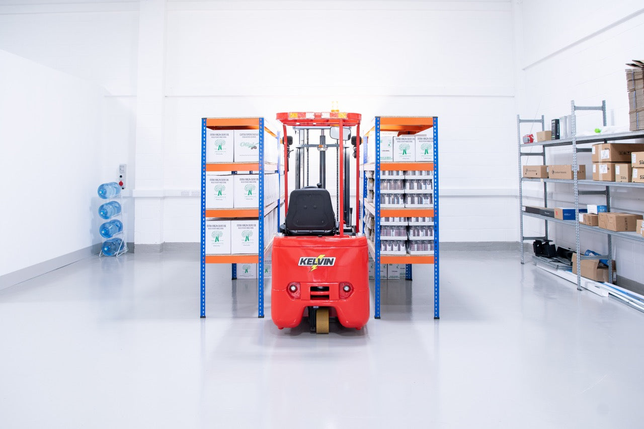 Red forklift in a warehouse with shelves and boxes.