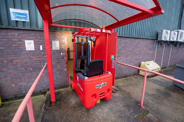 Red forklift in front of a brick building with a canopy